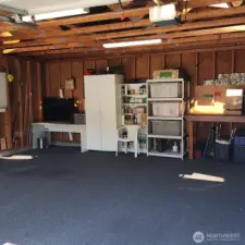 Garage is roomy with additional shelving and storage.