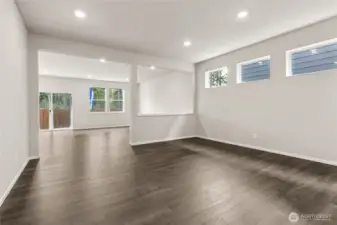 Open great room viewed from the dining area featuring hardwood floors, recessed lighting, three high windows, and a sliding glass door leading to the backyard patio. Photos are representative only and may display different color packages and/or upgrades.
