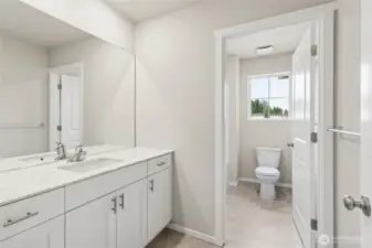 Spacious guest bathroom featuring a white vanity with quartz countertop, chrome hardware, a large mirror,  and a window providing natural light. Photos are representative only and may display different color packages and/or upgrades.