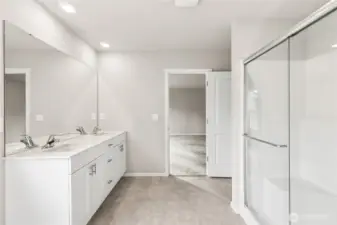 Primary bathroom showcasing the wide vanity, white quartz countertop, chrome faucets, large mirror, and a spacious walk-in shower with frameless glass doors. Photos are representative only and may display different color packages and/or upgrades.