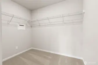 Spacious primary bedroom walk-in closet featuring wire shelving on three walls, plush carpet flooring, and neutral walls providing ample storage space. Photos are representative only and may display different color packages and/or upgrades.