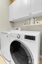 The laundry room is centrally located between the bedrooms and has cabinets above for added storage.  There is also a linen closet in the hallway for additional storage.