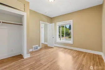 Unit A Bedroom #2 is all about versatility and charm. With pass-thru access to both the den and living room, it seamlessly flows into the rest of the home. A cute built-in shelving area adds a touch of character as you move into the den. The warm wood-tone laminate flooring and the huge picture window bring in natural light, making this room feel bright and inviting.