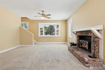 Step into the living room of Unit B, where cozy meets chic. The soft oatmeal carpeting creates a warm, inviting feel, while the brick hearth and wood-burning fireplace with its white mantle top bring all the charm. That massive bay window is the real showstopper, offering space for seating, plants, or a spot your kitty will claim as their own. It’s a room that’s designed for both lounging and living.