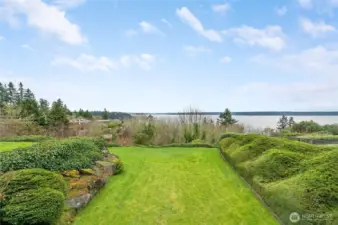 Expansive bluff-top lawn framed by sculpted hedges and natural stone, opening to sweeping water views. A serene, private setting perfect for relaxing or entertaining while enjoying the ever-changing scenery.
