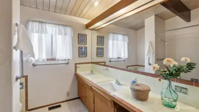 A bright and welcoming main level bath with dual sinks and classic mid-century character.