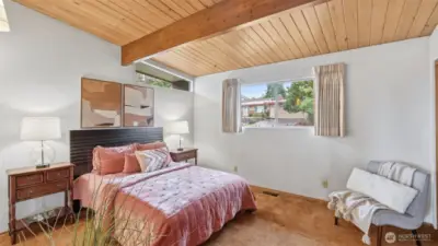 Retreat to this peaceful primary bedroom with warm wood ceilings and soft natural light.