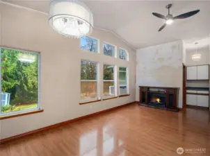Another angle of the great room/dining room that showcases the vaulted ceiling, abundant windows, a cozy fireplace feature and a coffee bar.