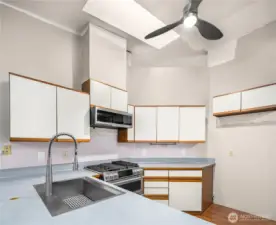 A skylight floods the kitchen with natural light. It boasts ample cabinetry with a modern farmhouse sink and faucet, disposal and stainless steel gas range with microwave and dishwasher.