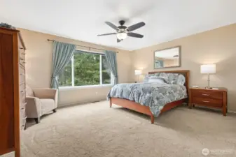 As we move upstairs, this is the primary suite - you enter with double doors and it features a ceiling fan, large window, and the 5 piece primary bath just to the right.