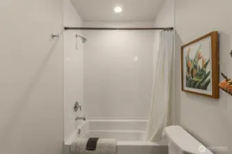 The bright and fresh bath area has a shower/tub combination and subtle decor touches that add warmth to the space.