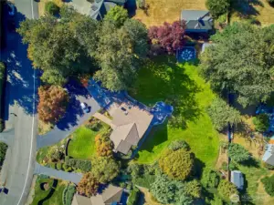 A drone shot showing the horseshoe driveway and the sunny expansive back yard.