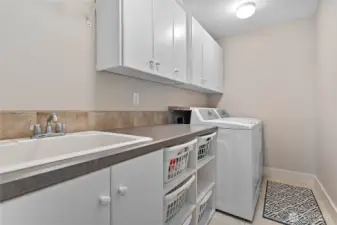 Handy upper level utility room with sink, additional storage, and folding area.