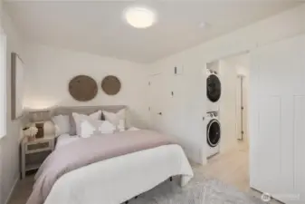 Upper-level bedroom featuring neutral finishes, modern design, and convenient access to in-unit stacked washer and dryer, offering functional living in this newly constructed Friday Harbor townhome.