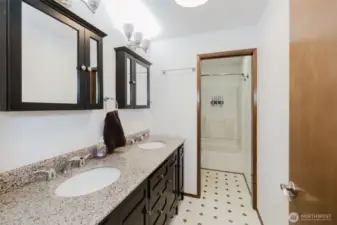 This bathroom includes polished granite countertops, dual sinks, and contemporary mirrors, offering a clean, streamlined look.