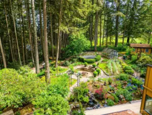 The expansive outdoor grounds feature a cozy fire pit, functional greenhouse, fun-filled trampoline, and a shed—all nestled amid mature trees and lovely shrubbery, offering the perfect blend of recreation and relaxation.