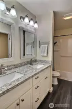 Full bath highlights a double vanity with elegant granite counters, combining style and functionality.