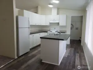Very Large Open Island Kitchen with White Cabinets and Appliances. New LED Lighting, Newer Counter Tops and Vinyl Plank Flooring.