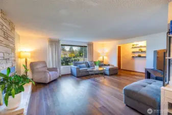 Bright, spacious living room with fireplace, stone mantel & beautiful floors