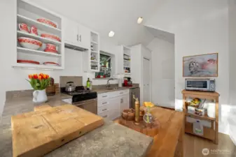 The kitchen has open shelving above and an a lot of storage white shaker in the drawers and cabinets.