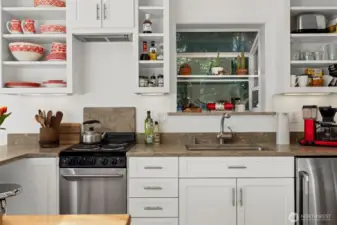 There is a small refrigerator to the right of the sink and a 4-burner stove to the left.