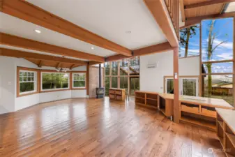 Sun-filled great room with expansive windows, vaulted wooden ceilings, and outdoor views.