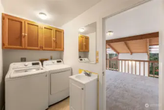 Laundry room with top-loading washer, dryer, and upper cabinets for extra storage.