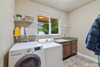 The roomy laundry room has all the amenities, including a spacious sink and plenty of storage. Washer and dryer stay!