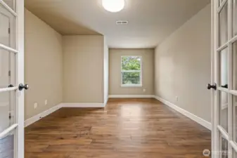 The roomy den/office features glass front French doors and hardwood floors. To the left is a spacious closet, making this a possible 6th bedroom.