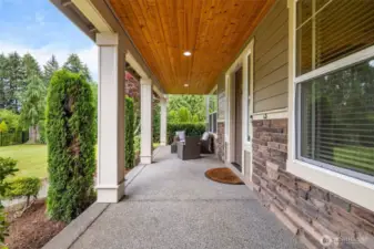 Spacious front porch with plenty of space for seating and colorful pots.