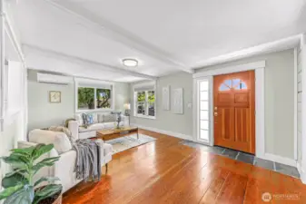 Bright living room with original and reclaimed wide board fir floors, large newer windows and beautiful wood front door.