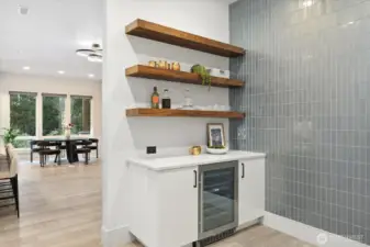 Full tile wall with floating shelves in this Butler’s pantry complete with beverage fridge