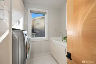 Handy location for laundry next to sleeping quarters with ample cabinets and utility sink