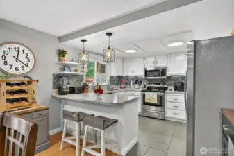Big kitchen with Corian Counters, tile back splash, & stainless appliances. Newer lighting pendants over the peninsula.
