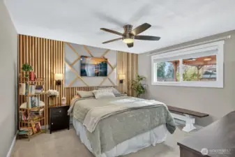 Primary Suite with designer slated wall, ceiling fan, and window with blinds.