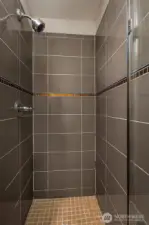 Primary shower, with frameless glass shower door.