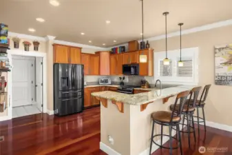 The chef’s kitchen features a gas range, cherry cabinetry, elegant wood floors, a dine-at bar counter, and generous counter space for cooking and entertaining.