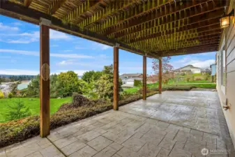 Enjoy outdoor living on the covered stamped concrete patio, with a boulder staircase providing access to the rest of the backyard.