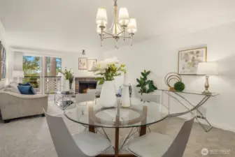 From the dining area, a view into the living room featuring a wood-burning fireplace and access to the deck beyond
