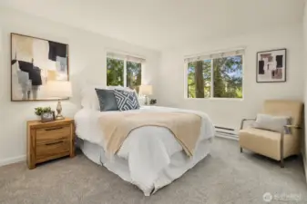 Entry into the primary bedroom reveals fresh carpet, two oversized Milgard vinyl windows (2022) with blinds, and a serene, wooded outlook