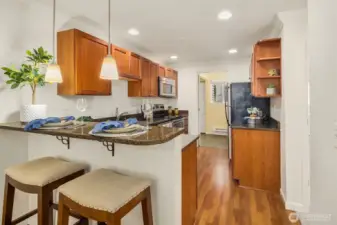 From the dining area, a welcoming view into the kitchen, featuring an eating peninsula and warm pendant lighting
