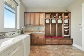 A large laundry room with sink and built-in cabinets.