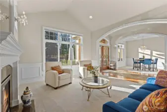 Formal living room with vaulted ceilings, wainscotting, and a dramatic fireplace