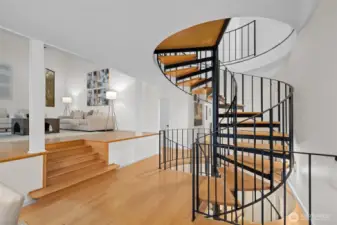 The spiral staircase is real work of art! With it's beautiful wide wooden stairs and gorgeous ironwork rail, it sweeps from the front entry on the lower floor all the way to the 2nd floor primary suite. This level is the main floor with beautifully elevated formal living room seen here on the left. The whole house is freshly painted, with newer carpets and new light fixtures throughout.