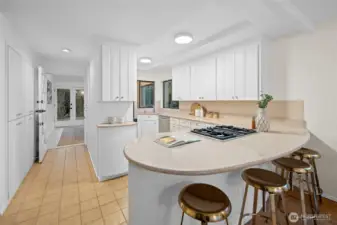 This bright, welcoming kitchen features new lighting and light airy colors that make the space feel open and uplifting. A gas cooktop with a hidden vent keeps the lines clean, while the wrap around layout offers an efficient and thoughtfully designed use of space with an abundance of cupboards for effortless storage. A charming Dutch door opens to the sun room and back yard, bringing in fresh air and an easy indoor outdoor connection. The curved peninsula offers comfortable seating for relaxed weekend breakfasts or casual gatherings with friends.