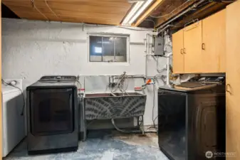 Laundry room has a lot of open storage area and a utility sink. The doorway to the backyard is on the backside of the cabinets on the right.