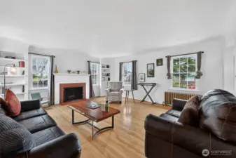 Living room with original hardwood floors, built ins and a cozy wood burningfireplace.