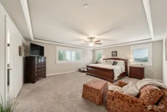 Owner's suite with plantation shutters, coffered ceiling and views of the forest.