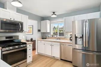 Stainless steel appliances with gas stove top, microwave, dishwasher, large fridge and pantry area.