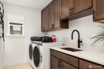 Laundry room is conveniently located upstairs and has beautuful cabinetry, utility sink and comes with a front loading washer and dryer